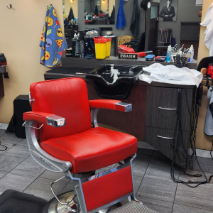 A red leather barber chair beside a wash station at Empire